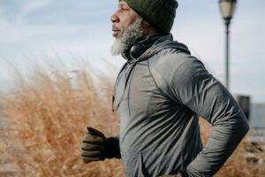 black pensioner in sportswear jogging in sunny autumn day